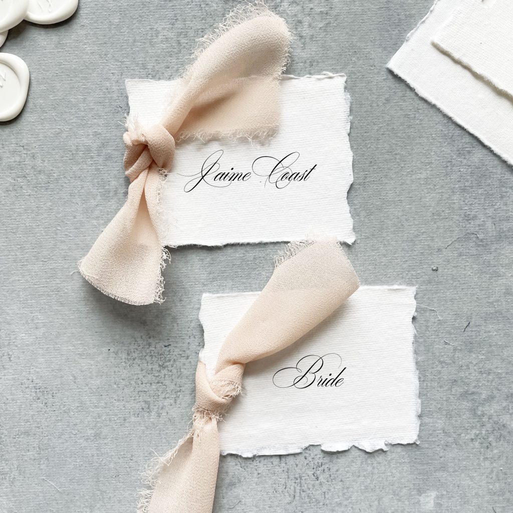 handmade paper place card with blush ribbon that says "bride" on it