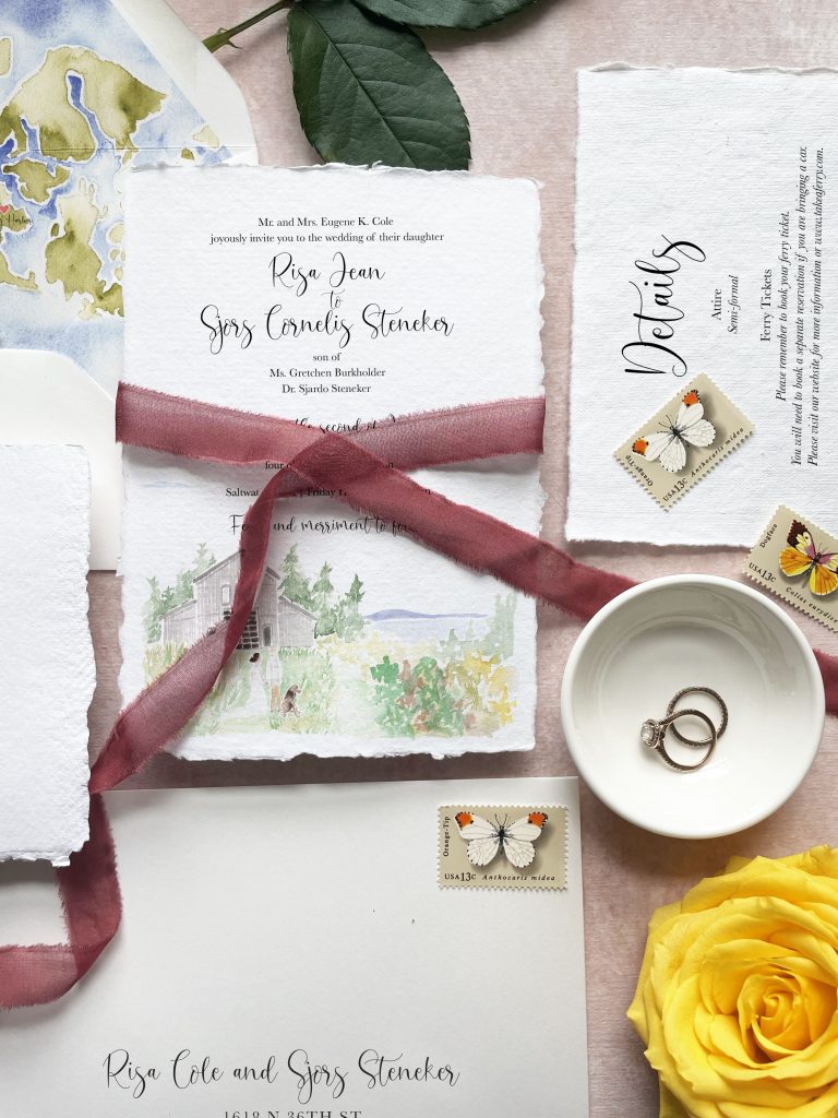watercolor wedding invitation suite on handmade paper with watercolor map of seattle with a burgundy silk ribbon on a pink background